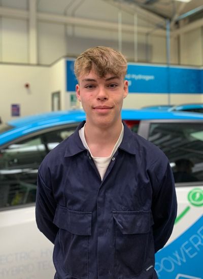 Leicester College student, Ben Williams, who is studying T level Motor Vehicle Engineering, standing in front of a car