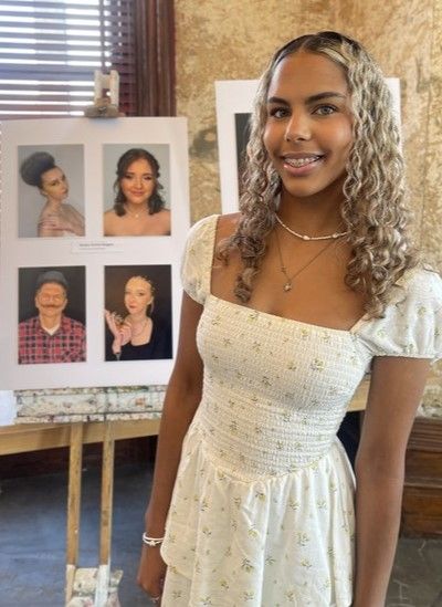 Leiceter College make-up artistry student, Savana Groves-Burgess, standing in front of images of her work