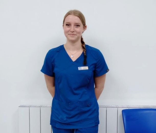 Leicester College student Anuszka standing with her arms behind her back and wearing a blue dental uniform