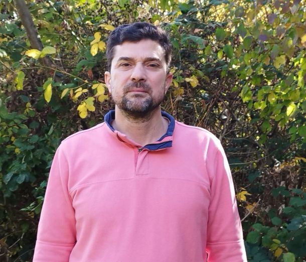 Adult Leicester College Student, Hadi wearing a pink coloured shirt standing in front of a hedge