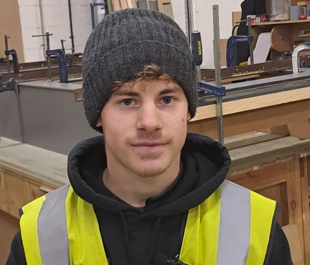 Carpentry and Joinery Apprenticeship student Mackenzie, wearing a hi viz jacket and grey hat