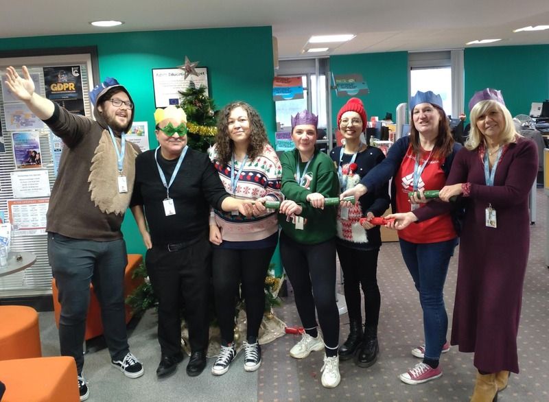 Leicester College staff pulling crackers ready for the Christmas Bake-off