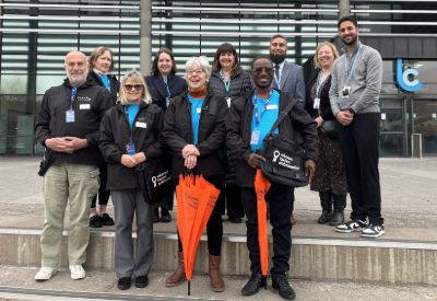 The Volunteer Tourism Ambassador team standing in front of the Leicester College Abbey Park Campus, wearing black and blue uniform