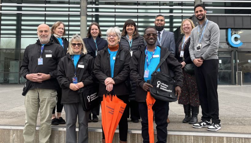 The Volunteer Tourism Ambassador team standing in front of the Leicester College Abbey Park Campus, wearing black and blue uniform