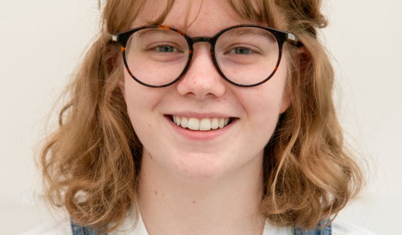 Leicester College graphic design lecturer, Lucy Stewart-Murray, who has red hair and wears glasses, facing the camera and smiling