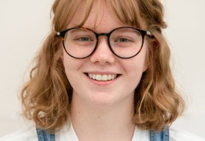 Leicester College graphic design lecturer, Lucy Stewart-Murray, who has red hair and wears glasses, facing the camera and smiling