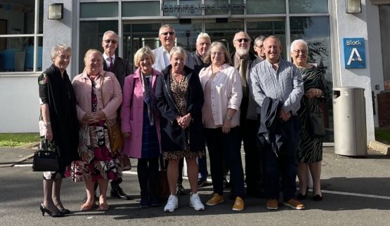 Group of former students outside a campus building gathered together to celebrate their 50 year reunion