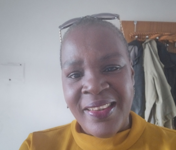 photo of adult learner wearing a yellow top and glasses onto of her head