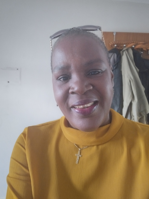 photo of adult learner wearing a yellow top and glasses onto of her head